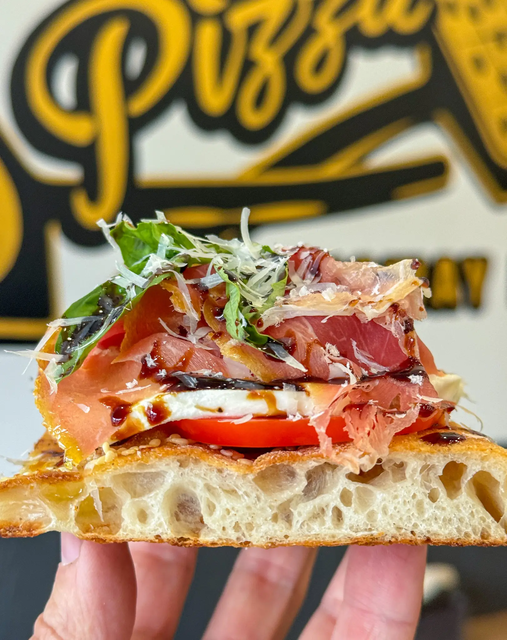 Italian focaccia sandwich from Crustinos Pizza, filled with fresh greens, cheese, and premium meats.